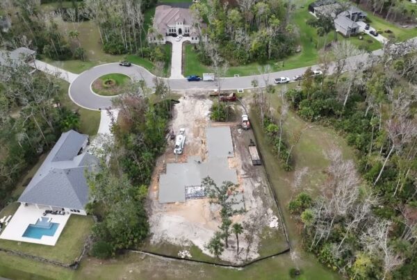 Image taken from drone looking down on new residential home build site with concrete slab foundation recently poured into frame