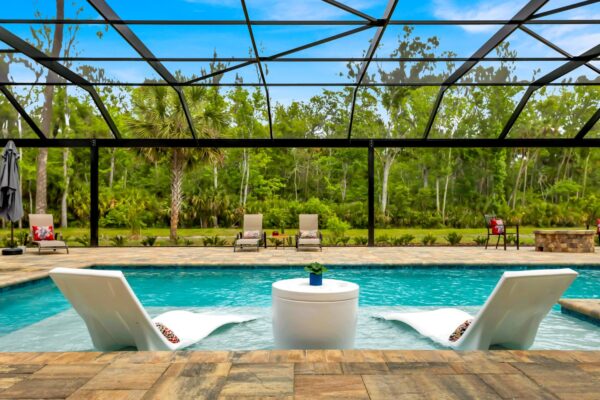 Japandi House pool with modern white lounge chairs on wading deck and full screen enclosure surrounding pool area