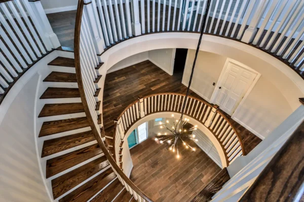 Bespoke custom home interior featuring architectural staircase design by Newberry Homes in Ponce Inlet, Florida featuring natural wood spiral. Unique one-of-a-kind light fixture art decor chandelier