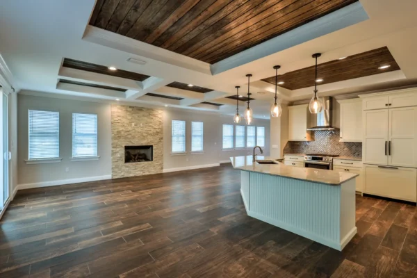 Coastal custom home designed and built by Newberry Homes in Ponce Inlet, Florida. Featuring beatuiful kitchen, with island, stainless steel stove and oven, refrigerator hidden by white cabinetry, fireplace built in brick. Beautiful natural wood highlights and one-of-a-kind light fixtures