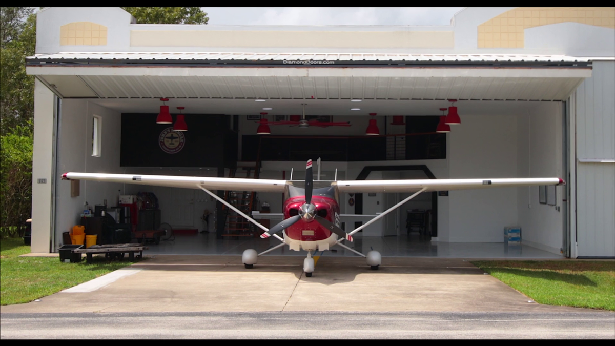 Hangar home by Newberry with garage bay door open and small airplane emerging from garage