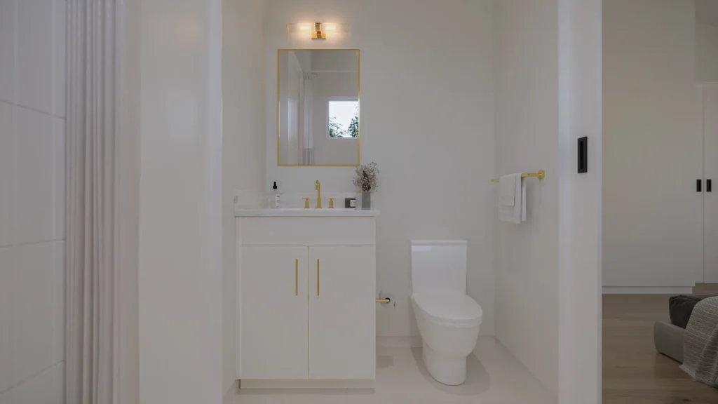 Charlotte model powder room with a white vanity, gold faucet, and gold-framed mirror at Six in the City, College Park, Orlando