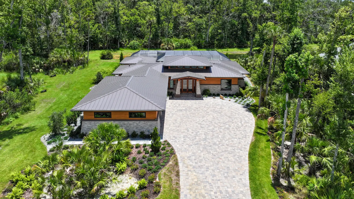 view of japandi home with curved driveway and natural landscaping