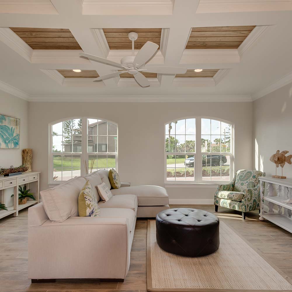 living room with white couches, large arched paned windows, a white fan and wood paneled coffered ceiling