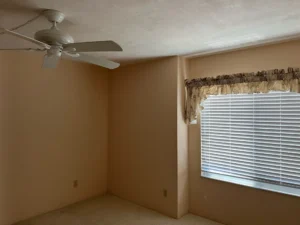 Before bedroom remodel featuring original carpet, window treatments, and lighting before transformation by Newberry Homes