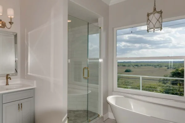 Luxury coastal master bathroom with freestanding tub, glass shower, and natural light designed and built by Newberry Homes in Ponce Inlet, Florida.