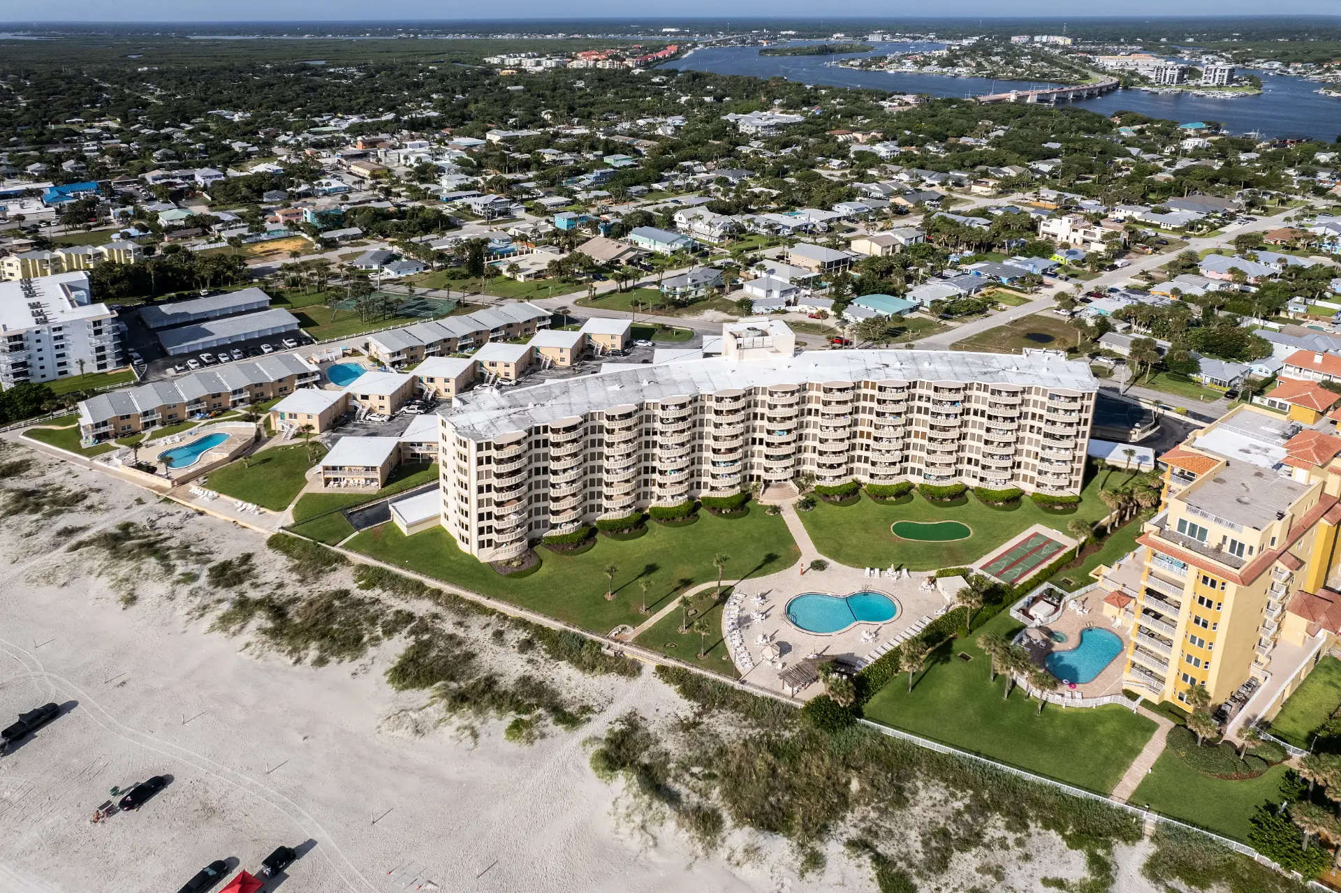 Aerial view of an oceanfront condo complex in New Smyrna Beach, Florida - south of Daytona Beach, highlighting the coastal setting of a Newberry Homes condo renovation. View of condo complex, pools, and sand from the beach.