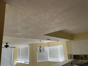Before view of condo kitchen showing original layout, finishes, and limited storage before renovation in New Smyrna Beach, Florida. Highlighting windows and ceiling fan