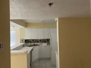 Original condo kitchen design before renovation, featuring outdated finishes and kitchen appliances in New Smyrna Beach, Florida.