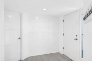 Updated condo entry hallway featuring shiplap detailing, modern doors, and light wood flooring by Newberry Homes in New Smyrna Beach, Florida.