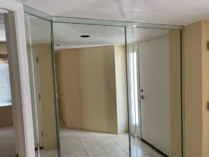 Original condo hallway with mirrored wall and dated finishes prior to renovation by Newberry Homes in New Smyrna Beach, Florida.