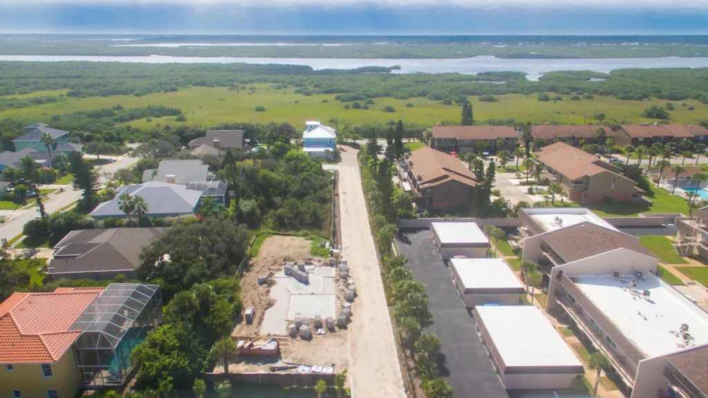 Aerial view of an empty residential lot prepared for a custom design build home by Newberry Homes in Deltona–Daytona Beach–Ormond Beach Metropolitan Area in Ponce Inlet. Surrounded by lush green lands and ocean views