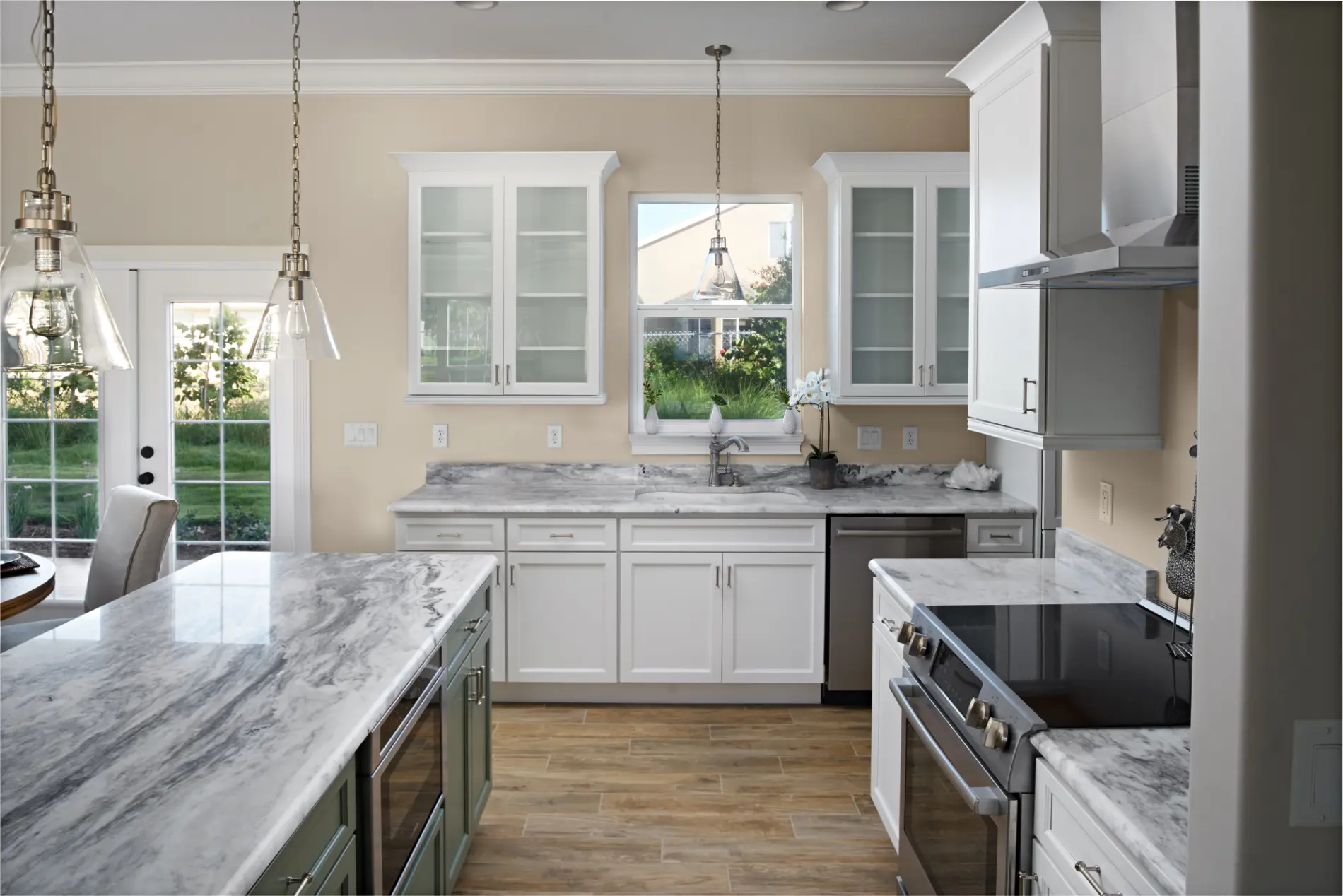 Kitchen view highlighting a custom opening, white cabinetry, marble countertops with a built in microwave, and pendant lighting in a custom design build home by Newberry Homes in Ponce Inlet Florida