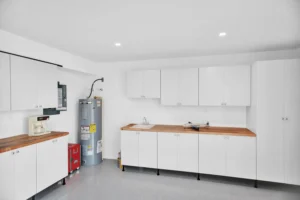 White workshop cabinetry with butcher block countertops, utility sink, and water heater in a Newberry Homes hangar home in Port Orange, Florida