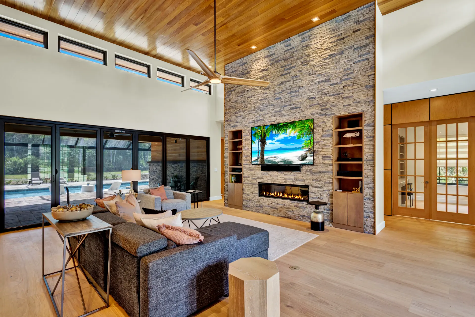 Open concept living room with vaulted ceilings, stone fireplace, and wood accents in a Newberry Homes Japandi custom home in Deltona–Daytona Beach–Ormond Beach, Florida Metropolitan Area