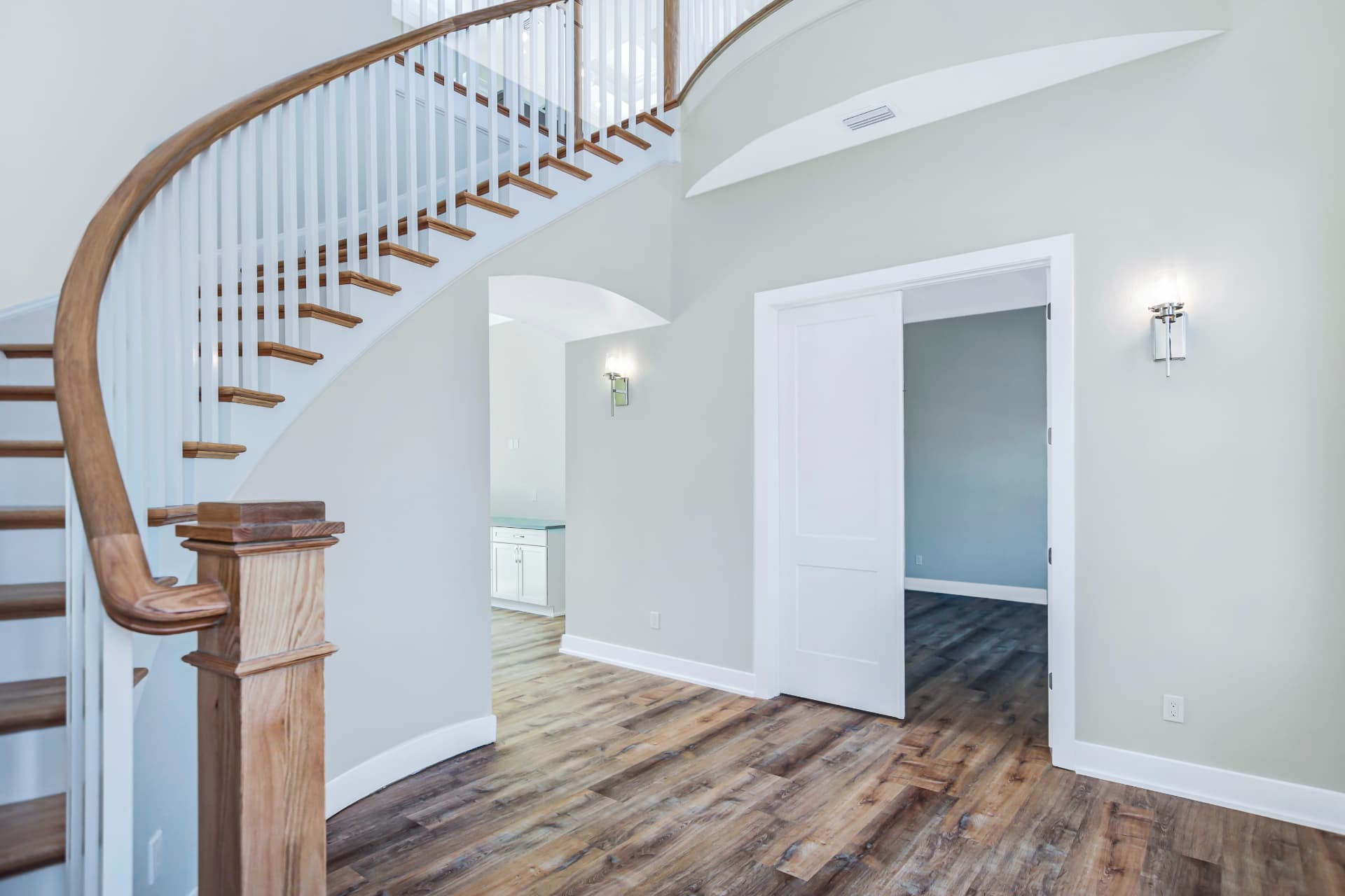 Completed luxury whole home remodel featuring a curved staircase and new interior finishes in Central Florida, double doors open into another room, entry into living room.