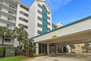 Exterior entrance of the Oceanquest condominium with a covered drive and tropical landscaping in Ponce Inlet, Florida, site of a Newberry Homes condo remodel.