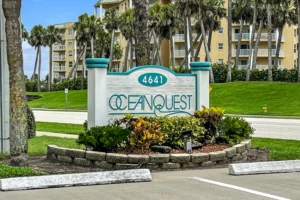 Entrance sign for the Oceanquest condominium at 4641 in Ponce Inlet, Florida, surrounded by palm trees and tropical landscaping, home to a Newberry Homes condo remodel.