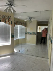 Before office remodel showing unused flex space prior to functional redesign by Newberry Homes in Central Florida. Floor to ceiling mirrors, ceiling fans, large window with outdated window coverings.