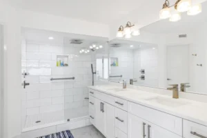 Primary bathroom remodel featuring an expansive glass walk-in shower, white subway tile, and a double vanity with quartz countertops in a Ponce Inlet condo by Newberry Homes.
