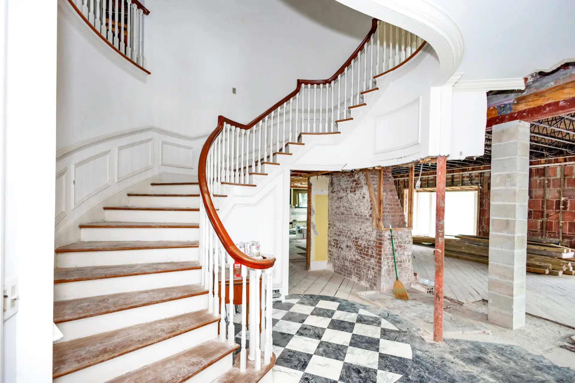 Interior of a home before a whole home remodeling project in Daytona Beach, Florida it shows the beginning of the demolition process. Curved stairs around old marbled flooring and missing walls - with brick and cinder blocks