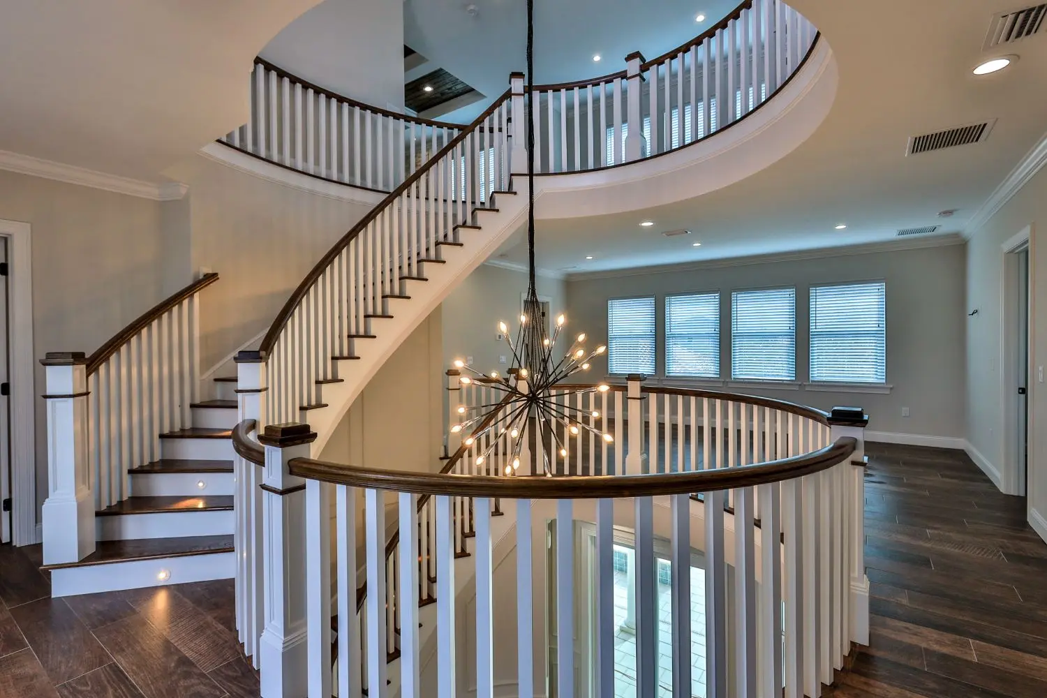 Curved staircase and two-story foyer with sputnik chandelier in The Mallory custom home by Newberry Homes, Volusia County, FL